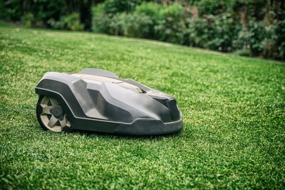 Ein Rasenmähroboter auf grünem Rasen.